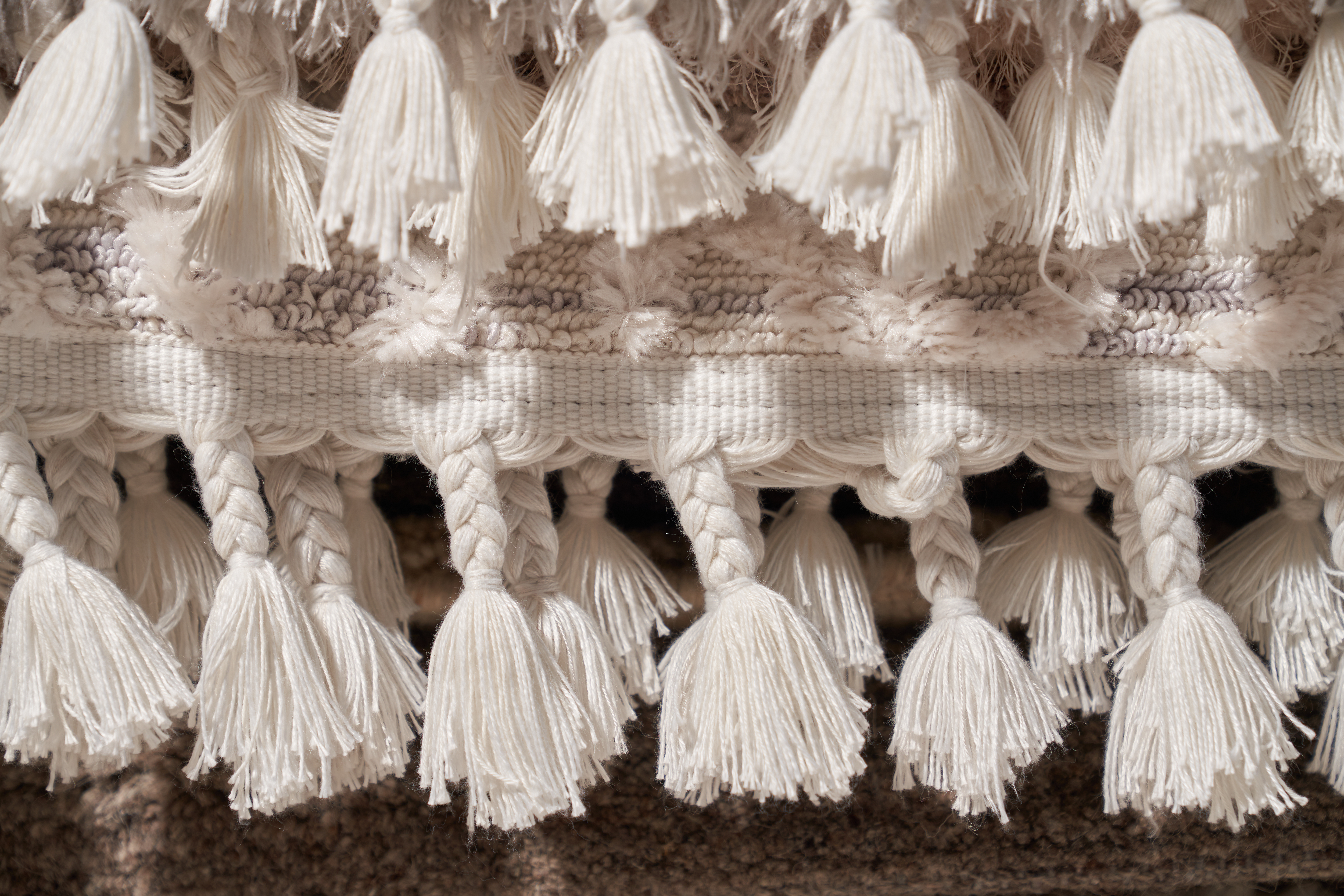 Textura de franja de algodão branco na borda do tapete bege como moldura.